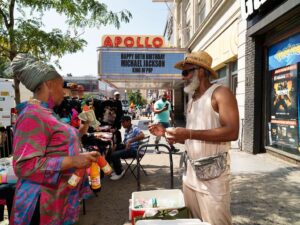 street vendors crowd the sidewalk outside the famous apollo theater