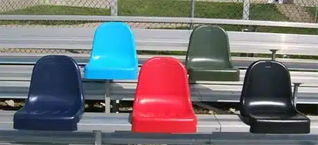 Five molded Tuf stadium seats in navy, light blue, red, green and black on bleacher supports